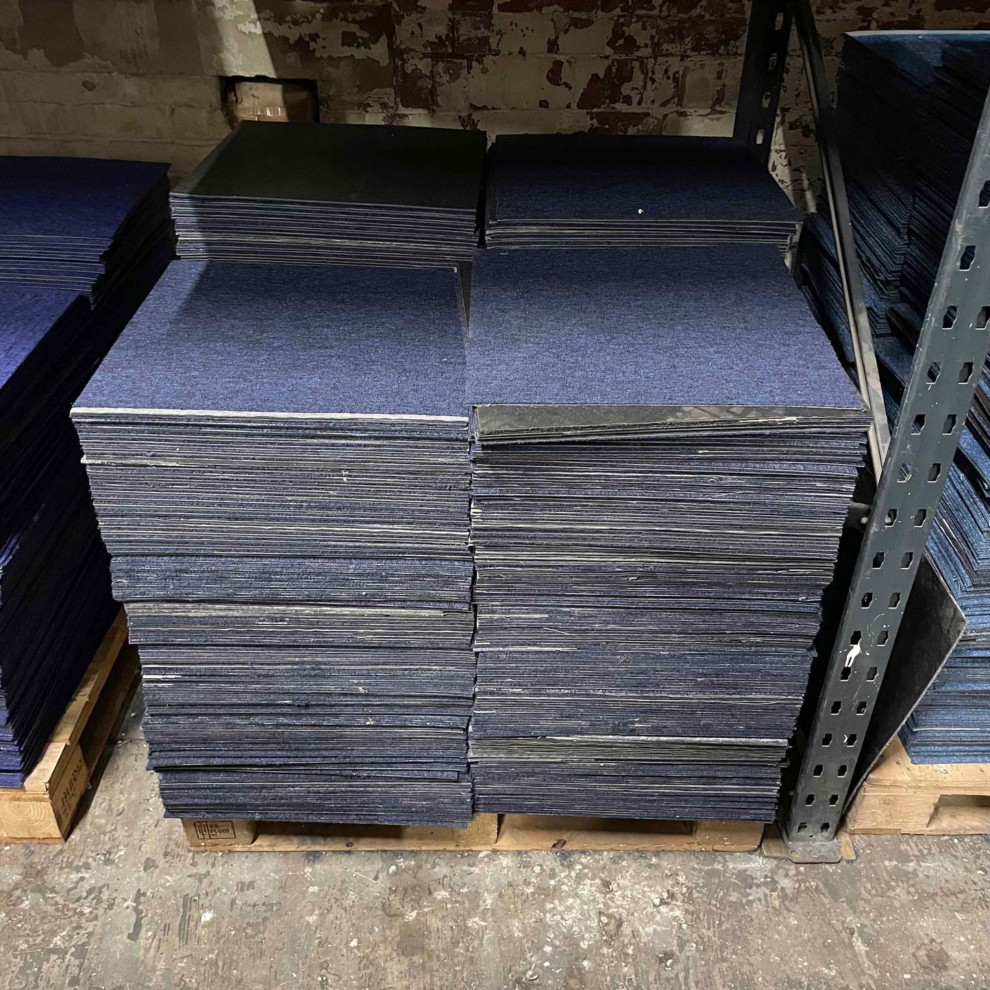 Dark blue carpet tiles, piled up on a pallet